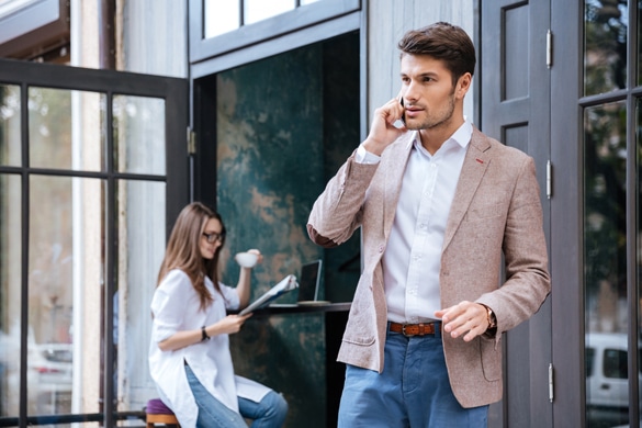 Attractive young stylish businessman talking on the mobile phone outdoors at the cafe - positive traits of the aquarius man